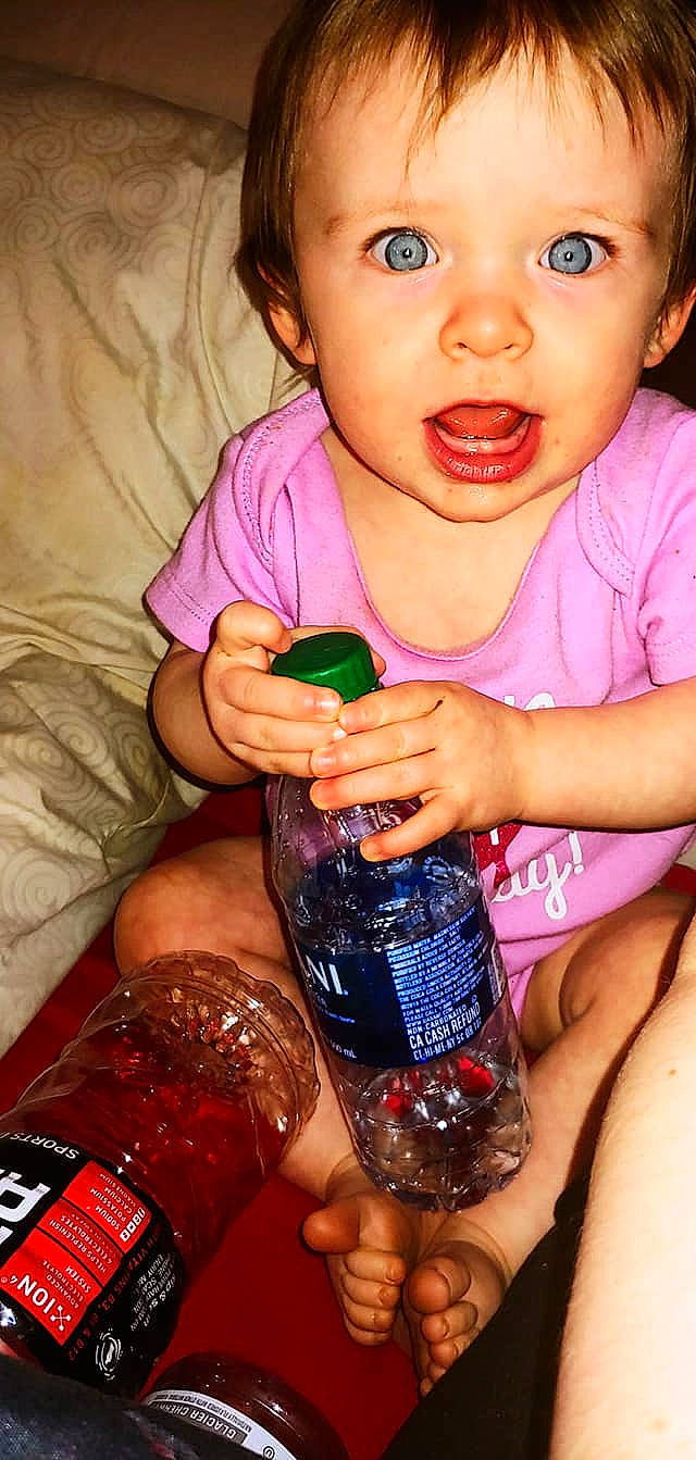 Rhea is registered to the contest to win money with this photo: baby_toddler_clothing, blue, bottle, cheek, drinkware, eyelash, finger, hand, happy, human, lip, liquid, nail, nose, organ, person, pink, plastic_bottle, product, skin