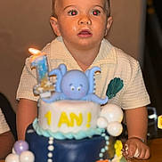 Paul André a rejoint le concours — aidez-le/la à gagner de superbes lots ! child, toddler, birthday_cake, cake, candle, number_one, octopus_figurine, celebration, party, table, hands, curious, messy, indoor, person, face, short_hair, white_shirt, blue, yellow