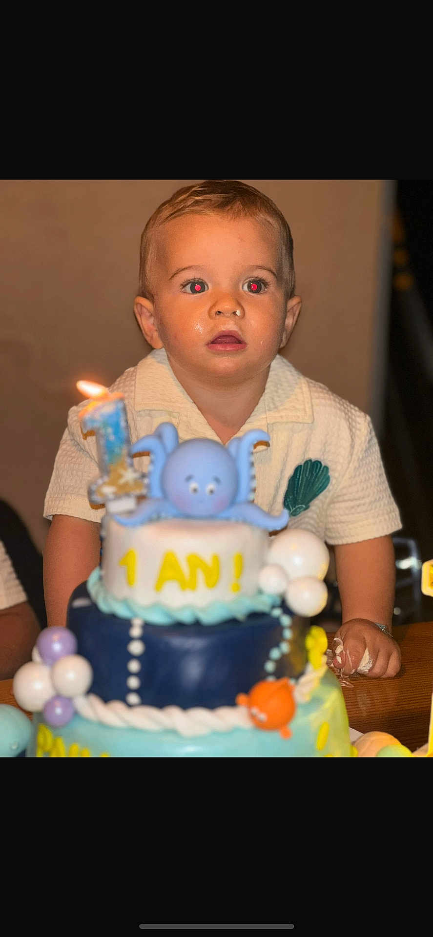 Paul André a rejoint le concours — aidez-le/la à gagner de superbes lots ! child, toddler, birthday_cake, cake, candle, number_one, octopus_figurine, celebration, party, table, hands, curious, messy, indoor, person, face, short_hair, white_shirt, blue, yellow