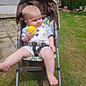 baby, stroller, yellow_ball, child, outdoor, grass, play, sunny, toy, park, seatbelt, happy, infant, summer, nature, childrens_toy, casual_clothing, foot, smile, person