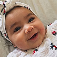 Amaia joined the competition — help win amazing prizes! apparel, baby, baby_girl, child, close_up, cute, eyelashes, face, happy, headband, infant, joyful, lying_down, portrait, skin, smiling, soft_lighting, strawberry_pattern, textile, white_clothing