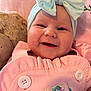 baby, smiling, headband, bow, pink_outfit, buttons, teddy_bear, soft_toy, closeup, face, infant, cute, happy, child, portrait, indoors, cozy, baby_clothing, baby_accessory, baby_bow