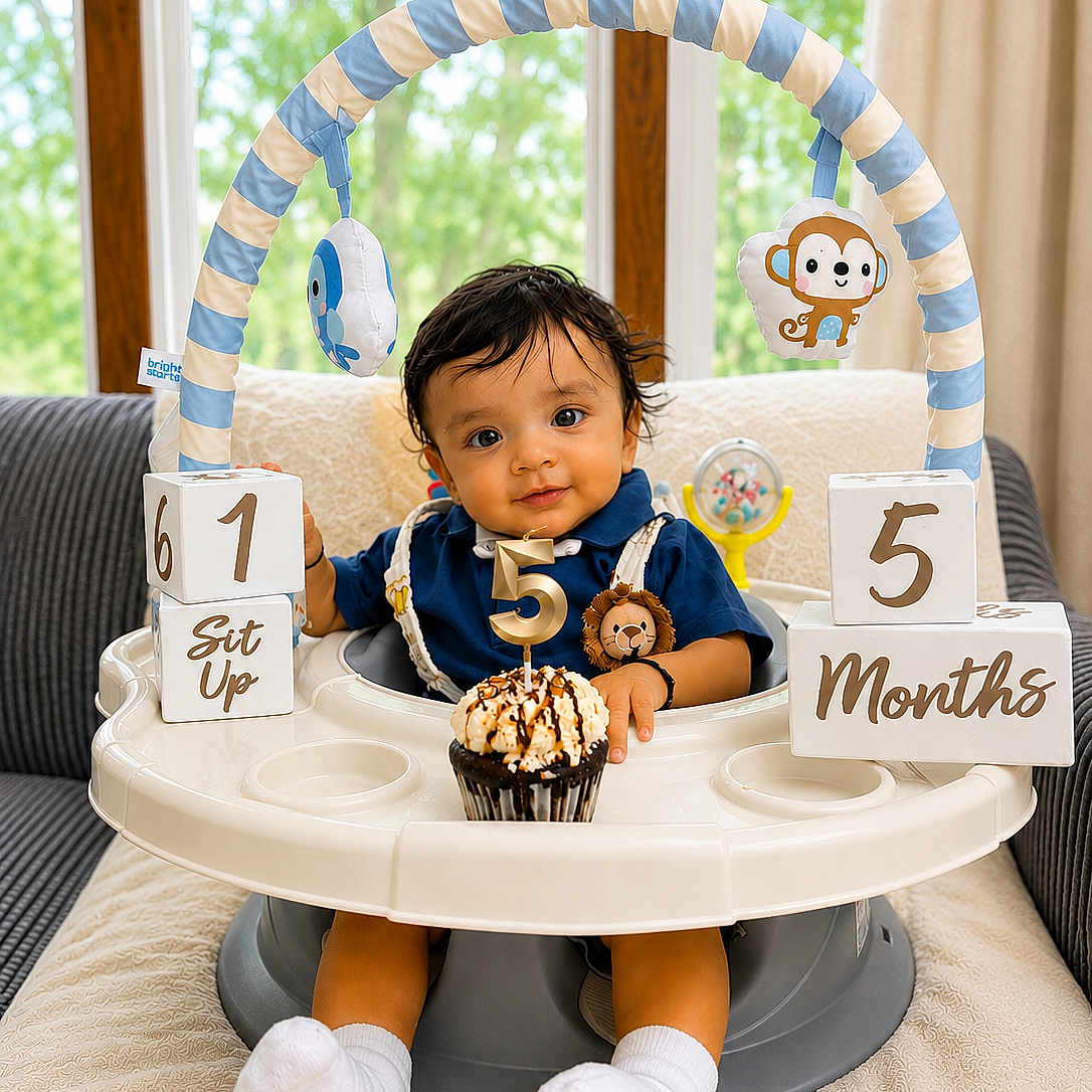 Rishiv is registered to the contest to win money with this photo: baby, infant, milestone_blocks, cupcake, number_candle, baby_seat, toy, hanging_toys, blue_outfit, white_socks, indoors, window, curtains, couch, blanket, smiling, portrait, child, celebration, cute