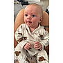 baby, infant, child, onesie, teddy_bear_pattern, sitting, hands, face, eyes, indoor, carpet, person, legs, skin, cute, portrait, young, apparel, comfort, curious