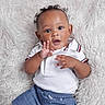 baby, child, curly_hair, white_polo_shirt, blue_shorts, fluffy_blanket, hand_gesture, cute, portrait, infant, smiling, indoors, happy, lying_down, skin, face, eyes, mouth, clothing, young