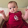 baby, child, red_dress, cute, portrait, couch, quilted, indoor, smiling, hands, face, person, young_child, blue_eyes, skin, sleeveless, clothing, sitting, expression, infant