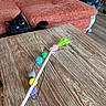 black_cat, cat, couch, orange_couch, wooden_table, cat_toy, feather_toy, indoor, pet, curious, furniture, home, living_room, playful, animal, feline, cozy, relaxation, colorful, closeup