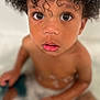 child, toddler, bath, water, bubbles, curly_hair, face, eyes, skin, mouth, nose, expression, sitting, indoors, closeup, portrait, wet, innocence, baby, person