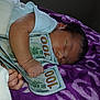 Sofia is registered to the contest to win money with this photo: baby, newborn, sleeping, money, hundred_dollar_bills, blanket, purple, white_wrap, hand, face, infant, cute, peaceful, indoors, soft_texture, portrait, resting, closeup, child, cash