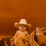 Braxton is registered to the contest to win money with this photo: baby, infant, child, cowboy_hat, cowboy_theme, saddle, rope, leather, blanket, rustic, portrait, seated, indoor, brown_tones, western, fashion, cute, face, photography, ranch