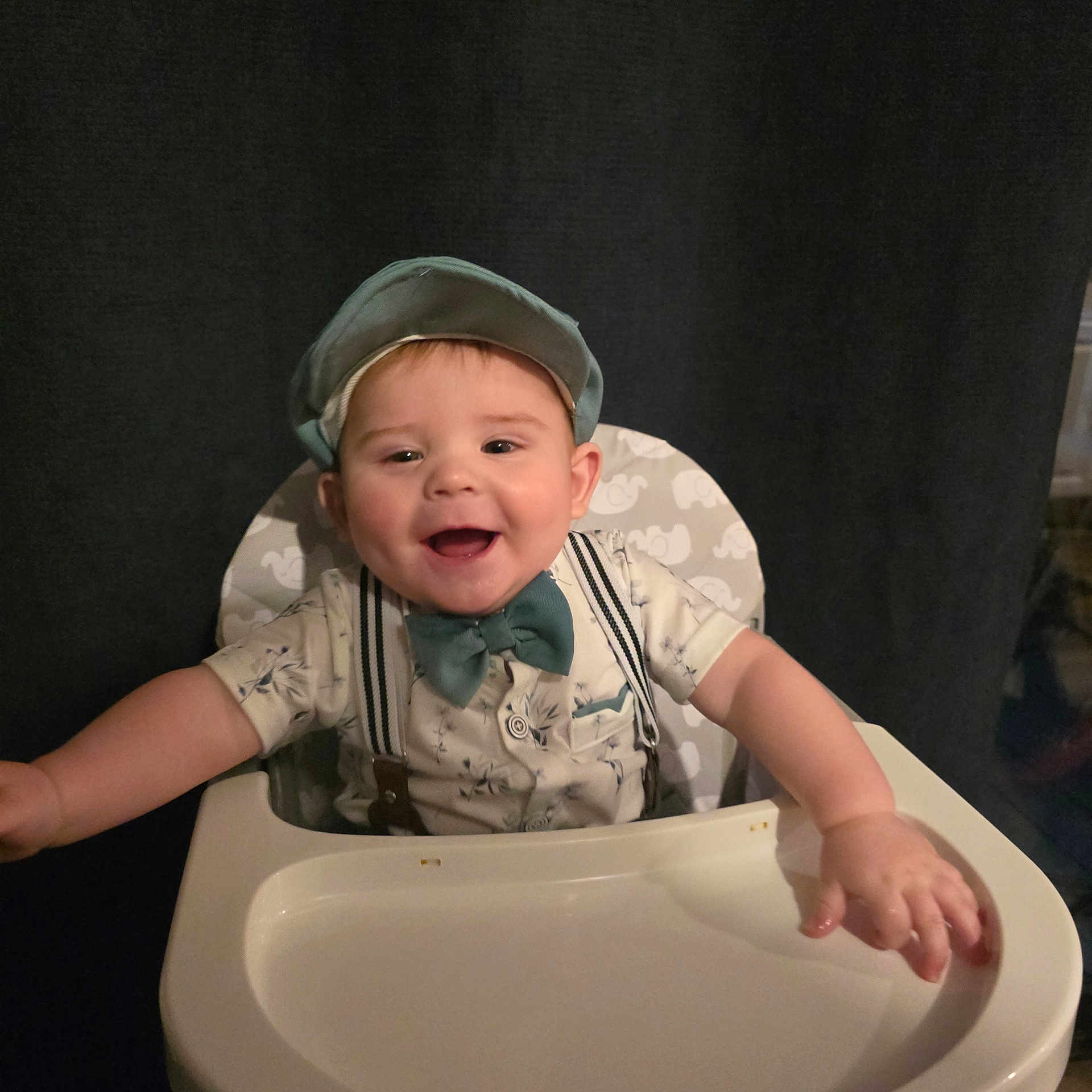 Aiden is registered to the contest to win money with this photo: baby, child, high_chair, smiling, bow_tie, cap, happy, infant, sitting, clothing, face, person, cute, portrait, indoors, furniture, arms_outstretched, baby_fashion, young_child, background