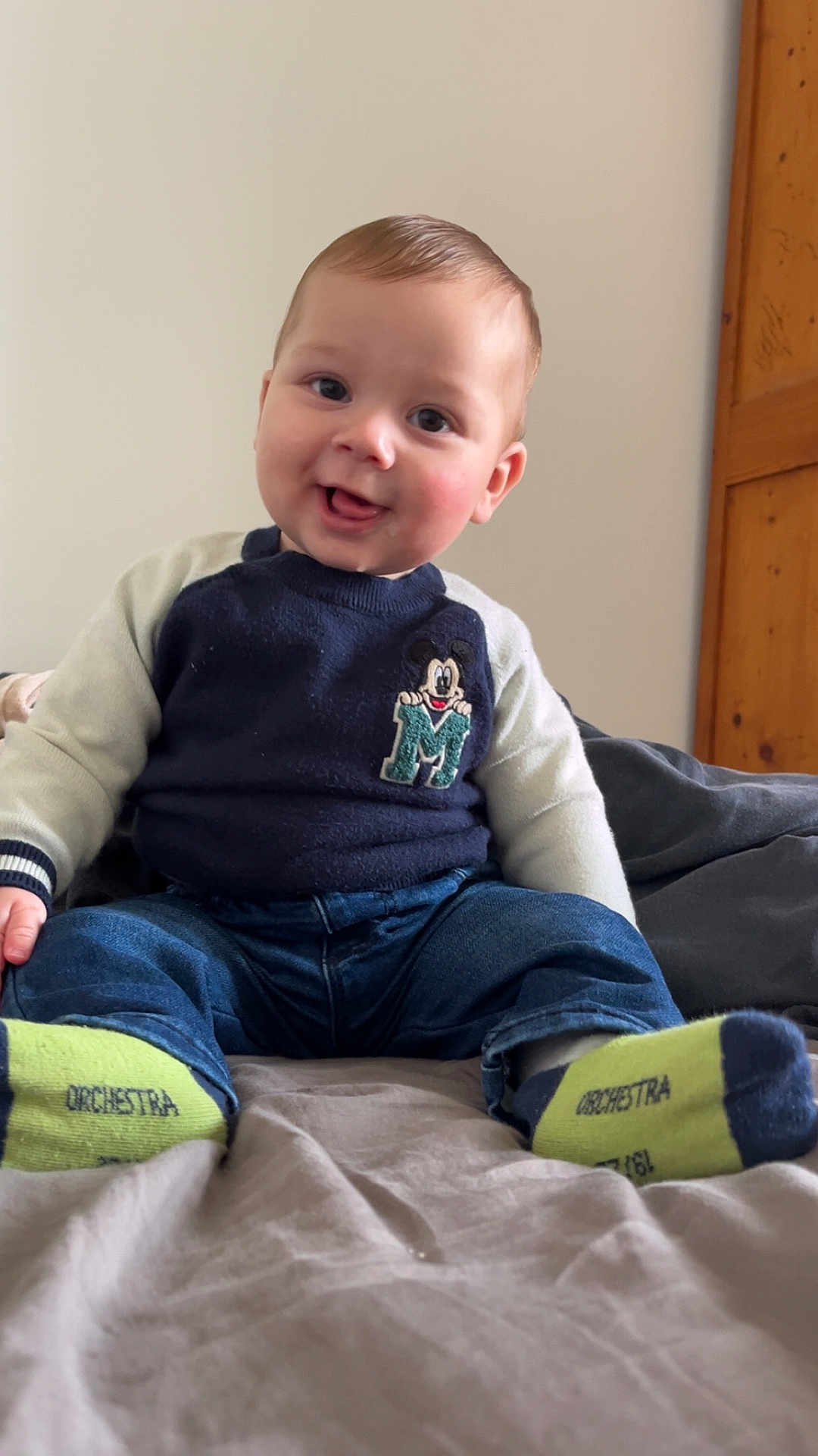 Lélio participe au concours pour gagner de l'argent avec cette photo : baby, child, smiling, sitting, socks, sweater, jeans, bed, indoor, cute, face, person, clothing, happy, portrait, young, toddler, room, wooden_furniture, casual