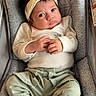 Skyla is registered to the contest to win money with this photo: baby, infant, headband, bow, baby_carrier, socks, clothing, pattern, cute, portrait, child, resting, indoors, soft_lighting, person, small_hands, green_pants, white_shirt, expression, comfortable