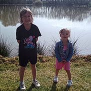 Rosemary Maëlys participe au concours pour gagner de l'argent avec cette photo : child, children, denim_jacket, glasses, grass, lake, nature, outdoors, pink_dress, portrait, reflection, shadows, shoes, shore, smiling, sneakers, standing, t_shirt, trees, water