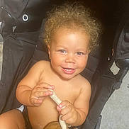 Deavon participe au concours pour gagner de l'argent avec cette photo : toddler, child, curly_hair, smile, stroller, plush_toy, bare_chest, hands, happy, indoor, person, infant, cute, baby, seat, toy, skin, face, expression, childhood