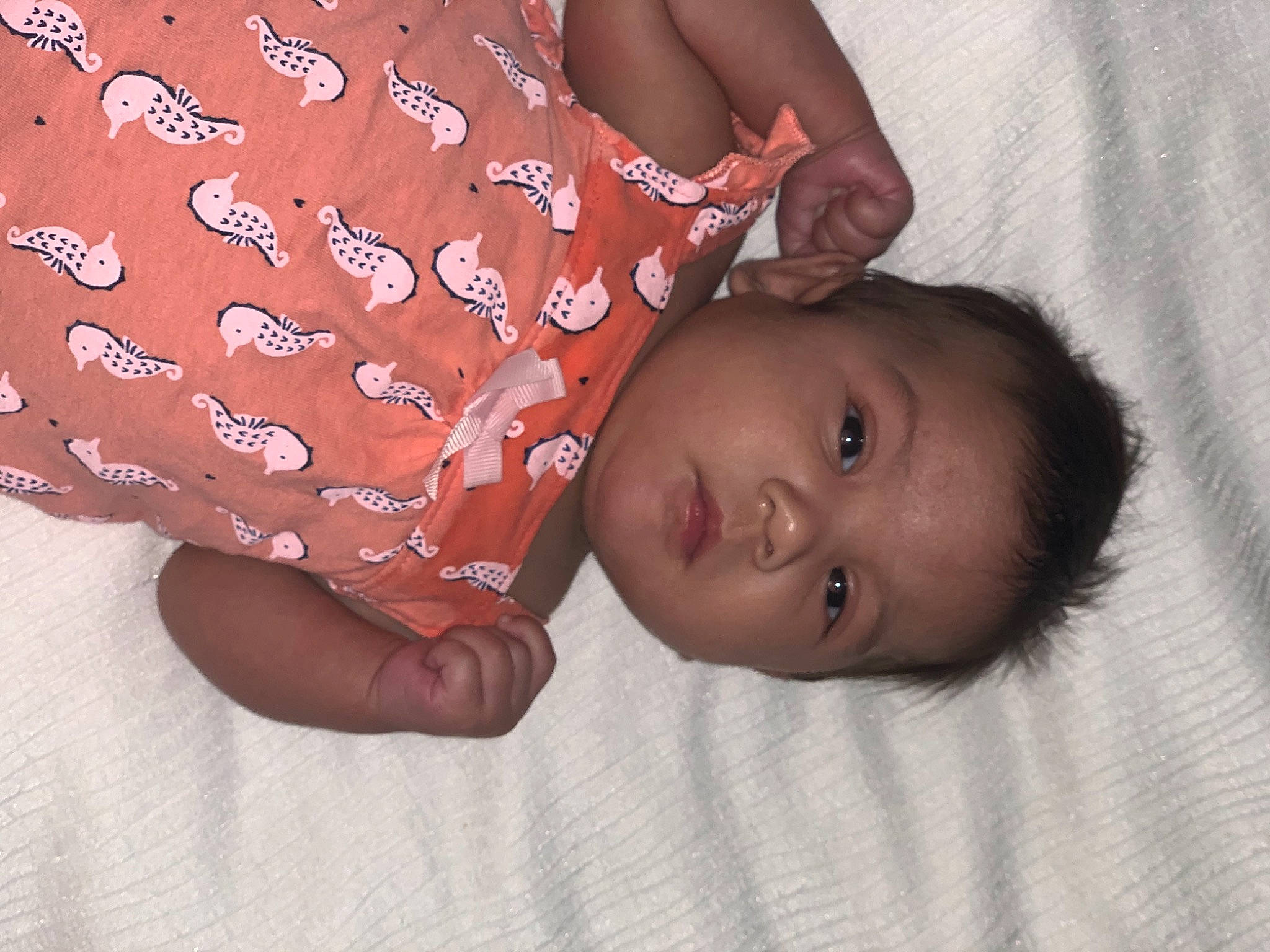 Maya is registered to the contest to win money with this photo: arm, baby, baby_toddler_clothing, cheek, child, comfort, finger, gesture, hand, happy, human_body, linens, lip, mouth, nose, pattern, person, skin, sleeve, thumb