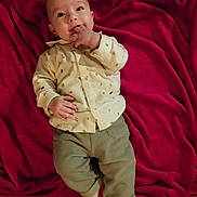 Camille a rejoint le concours — aidez-le/la à gagner de superbes lots ! baby, blanket, child, clothing, comfortable, cute, face, hand, happy, indoors, infant, lying_down, pants, person, red_blanket, shirt, smiling, socks, soft, young