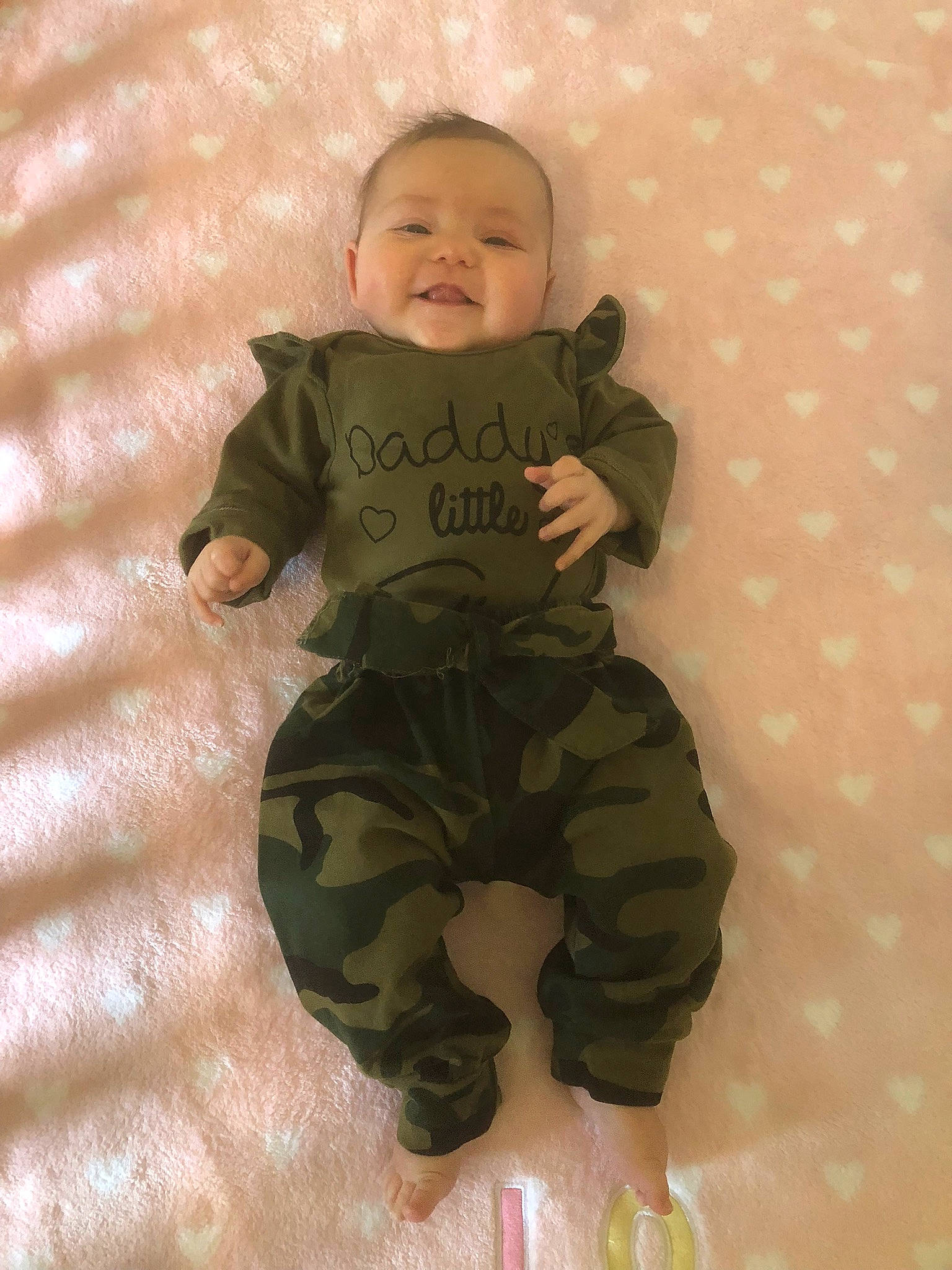 Vanessa is registered to the contest to win money with this photo: arm, baby, baby_toddler_clothing, camouflage, cargo_pants, child, comfort, fun, gesture, happy, head, linens, military_camouflage, pattern, person, skin, sleeve, smile, textile, thumb