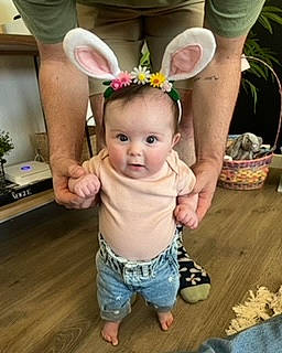 Lennon is registered to the contest to win money with this photo: baby, baby_toddler_clothing, child, eye, eyelash, fashion_accessory, flooring, flowerpot, fun, grass, happy, hardwood, headband, headpiece, person, pink, plant, sleeve, smile, toddler