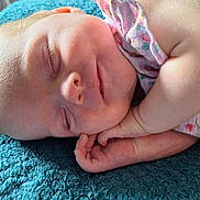 Ophelia is registered to the contest to win money with this photo: baby, sleeping, infant, hand, face, blanket, textile, skin, closeup, peaceful, cute, child, portrait, soft_light, floral_clothing, rest, newborn, adorable, comfort, relaxation