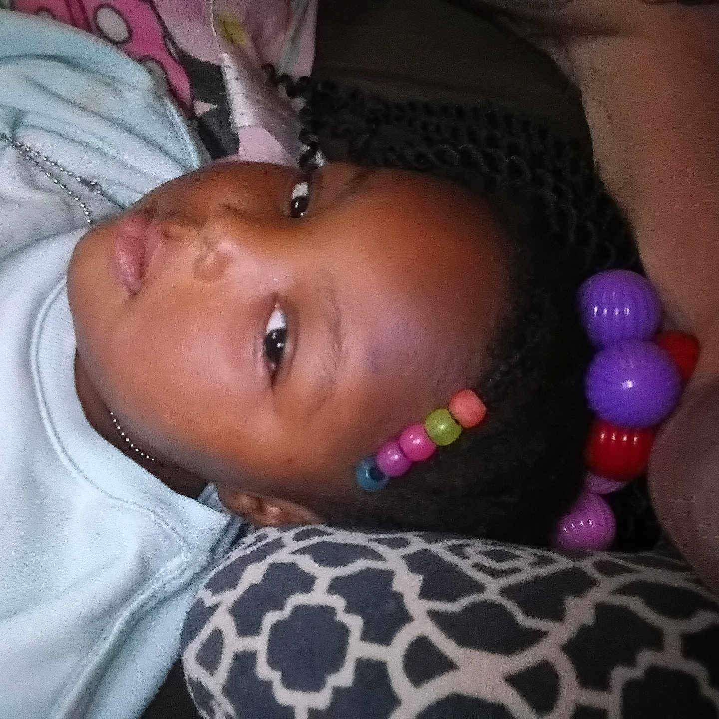 Va'Neyia is registered to the contest to win money with this photo: beads, black_hair, braids, casual, child, closeup, colorful, comfort, face, head, indoor, looking, pattern, person, pillow, portrait, relaxed, resting, sweatshirt, young