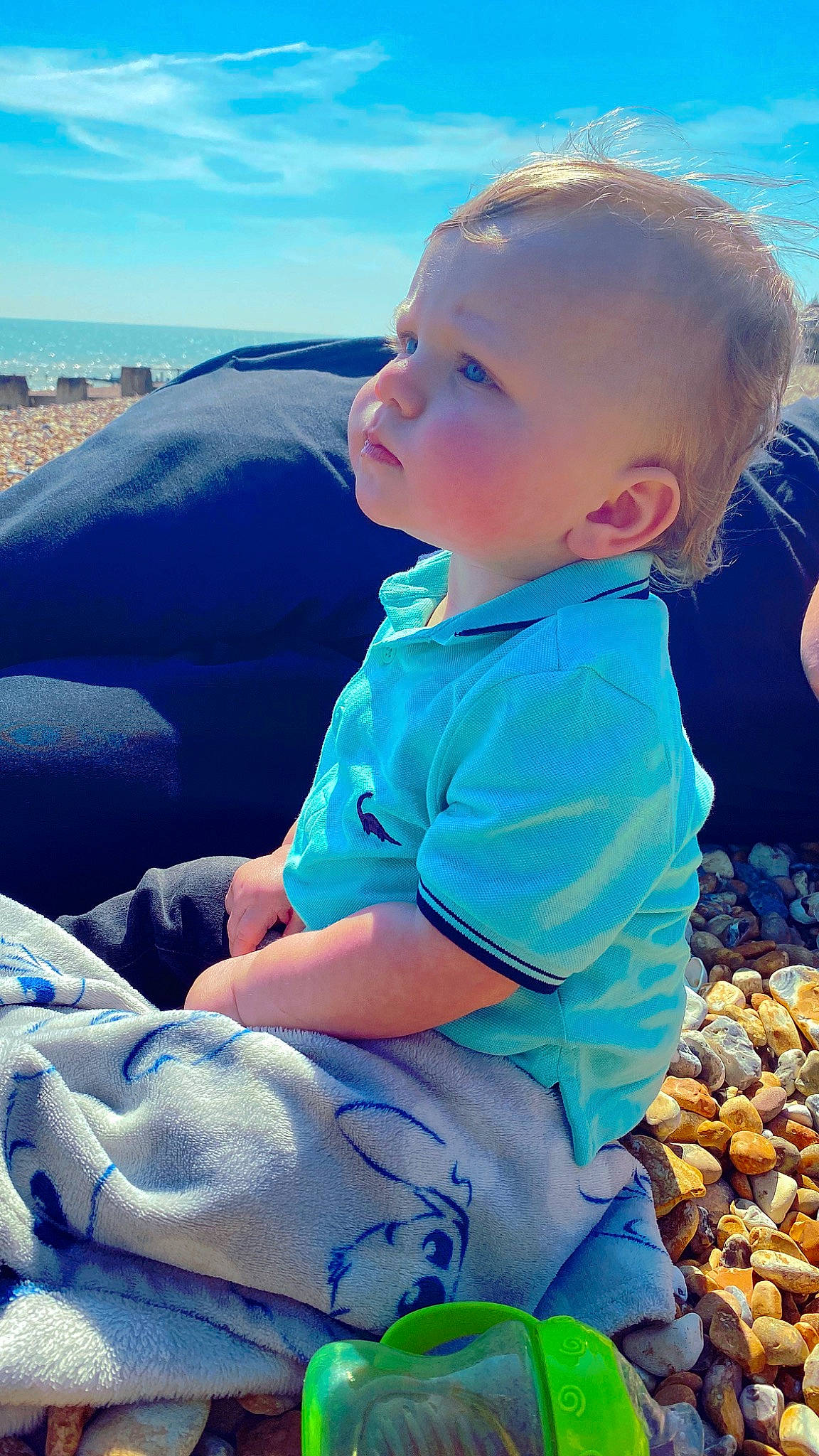 Harvey is registered to the contest to win money with this photo: azure, baby, baby_toddler_clothing, blue, body_of_water, child, comfort, cool, electric_blue, fun, grass, happy, lap, leisure, people_in_nature, person, sitting, sky, sunlight, toddler