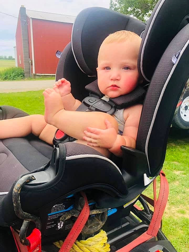 Frederick is registered to the contest to win money with this photo: auto_part, automotive_design, automotive_exterior, baby, baby_carriage, baby_products, baby_toddler_clothing, car_seat, car_seat_cover, chair, comfort, grass, lap, motor_vehicle, person, plant, sitting, tire, toddler, vehicle_door