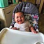 Kash is registered to the contest to win money with this photo: baby, high_chair, smiling, food, kitchen, tray, baby_clothing, hand, face, happy, infant, seat, domestic_interior, tableware, utensil, tissue, cabinet, cup, appliance, floor