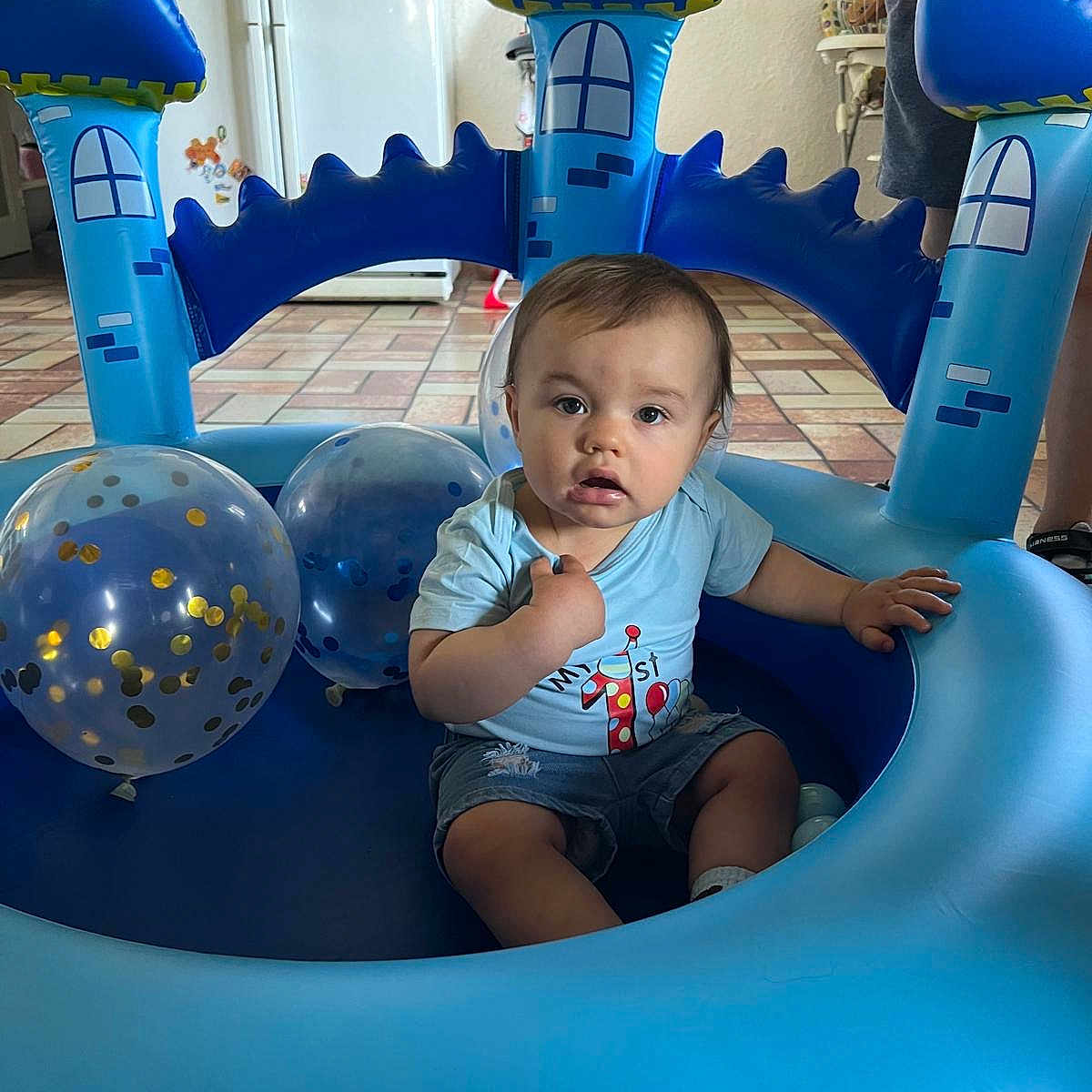 Lyam participe au concours pour gagner de l'argent avec cette photo : balloons, birthday, blue, child, confetti, cute, expression, floor, home, indoor, inflatable_castle, kitchen, person, play, refrigerator, shorts, sitting, tiles, toddler, tshirt