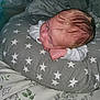 baby, infant, pillow, star_pattern, bed, blanket, floral, sleeping, resting, indoors, person, skin, hair, hand, face, clothing, white_sleeve, cute, newborn, cozy
