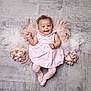 baby, child, smiling, pink_dress, tights, curly_hair, floor, flowers, tulle, fluffy_mat, happy, portrait, indoor, infant, cute, person, lying_down, soft_texture, studio_shot, head