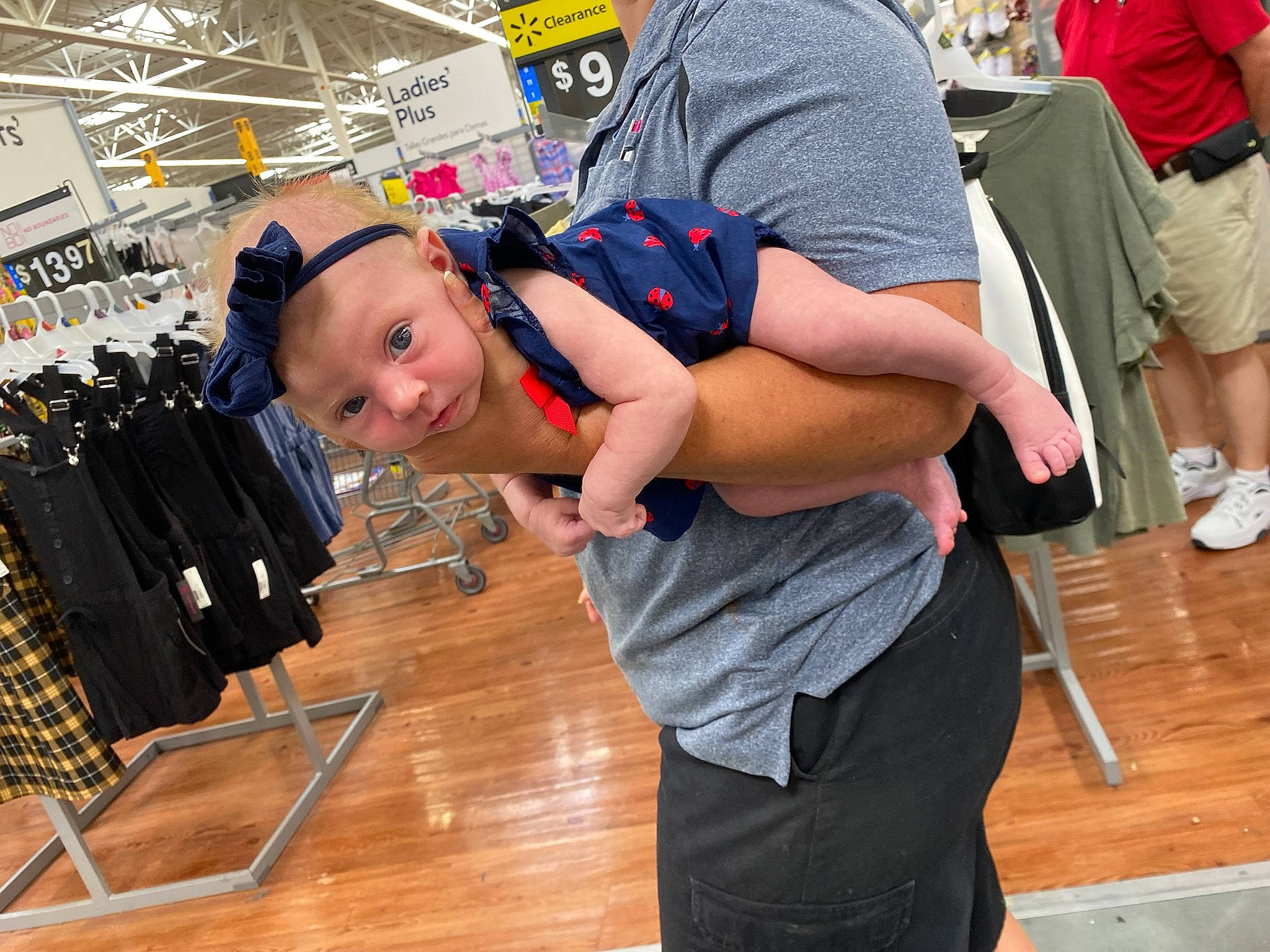 Brynn is registered to the contest to win money with this photo: arm, bag, baseball_cap, child, event, flooring, fun, hardwood, hat, headwear, joint, leisure, luggage_and_bags, person, retail, shoe, shorts, sneakers, t_shirt, toddler