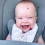 Lottie is registered to the contest to win money with this photo: baby, smiling, blue_eyes, bib, cushion, seat, infant, child, happy, face, skin, clothing, portrait, closeup, cute, sitting, indoor, young, expression, person