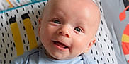 Erik joined the competition — help win amazing prizes! baby, smiling, face, blue_onesie, blanket, pattern, infant, cute, happy, portrait, child, lying_down, skin, head, eyes, mouth, indoors, closeup, baby_clothing, expression