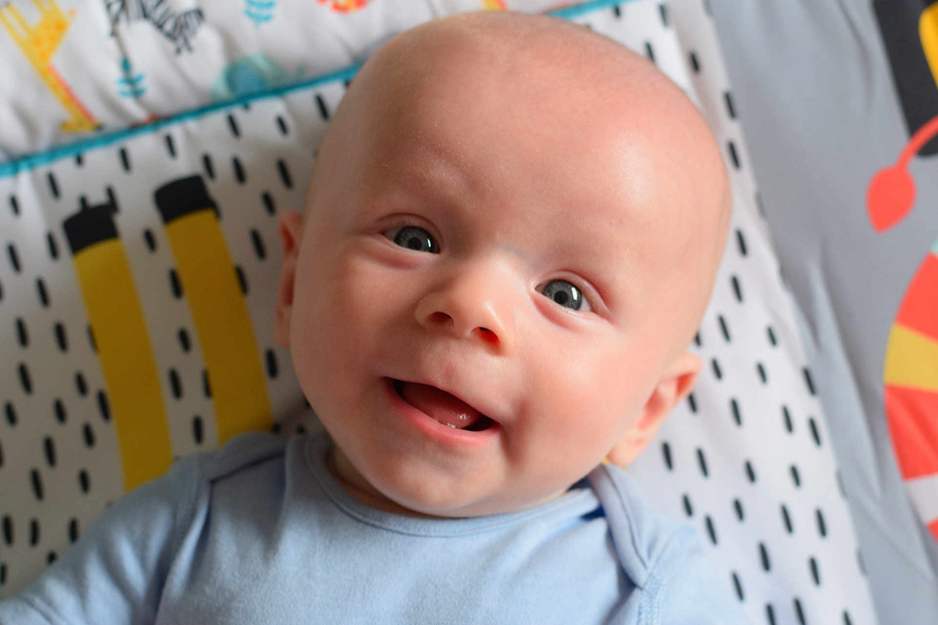Erik joined the competition — help win amazing prizes! baby, smiling, face, blue_onesie, blanket, pattern, infant, cute, happy, portrait, child, lying_down, skin, head, eyes, mouth, indoors, closeup, baby_clothing, expression