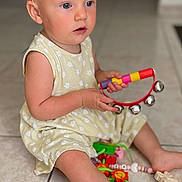 Victoria Grorod participe au concours pour gagner de l'argent avec cette photo : toddler, child, blonde_hair, blue_eyes, yellow_dress, sitting, floor, tiles, tambourine, toy, colorful, indoor, pacifier, foot, play, curious, young_child, person, baby, cute