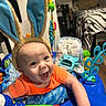 Cole is registered to the contest to win money with this photo: baby, bedroom, blue_activity_center, bunny_ears, cheerful, child, colorful, cushion, face, furniture, happy, headwear, indoor, infant, orange_shirt, person, playtime, seat, smiling, toys