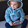 Robin joined the competition — help win amazing prizes! child, toddler, blue_hoodie, toy, sitting, cushion, bench, casual_clothing, smile, face, eyes, hands, footwear, indoor, portrait, cute, young_child, warm_clothing, playful, relaxed