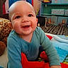 baby, child, smiling, plush_toy, blue_clothing, indoor, playroom, colorful, blanket, toy, happy, face, person, crawling, cute, infant, warm, soft, floor, young