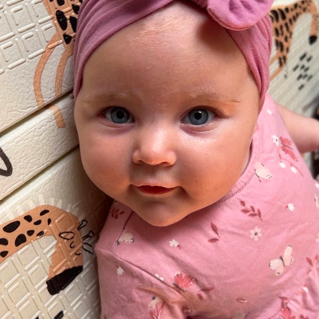 Harper-Marie is registered to the contest to win money with this photo: apparel, baby, blue_eyes, child, closeup, cute, face, floral_pattern, giraffe_pattern, headband, indoor, infant, looking, person, pink_bow, pink_dress, portrait, skin, toddler, wall