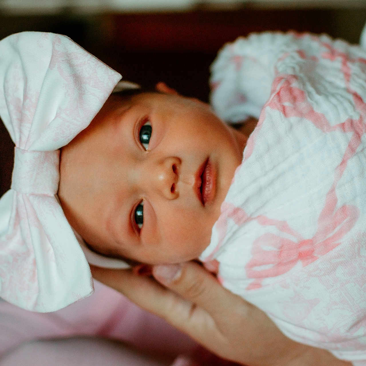 Sara is registered to the contest to win money with this photo: baby, blanket, bow, cute, eyes, face, gentle, hand, headband, indoors, infant, newborn, newborn_baby, person, pink, portrait, sleepy, soft, white, wrapped