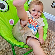Ronin is registered to the contest to win money with this photo: child, toddler, smile, playful, chair, green_chair, frog_design, indoor, carpet, shorts, tshirt, barefoot, foot, face, person, home, wall, floor, cute, happy