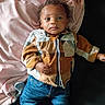 baby, infant, child, blanket, clothing, jeans, socks, shirt, portrait, indoor, curly_hair, face, lying_down, soft_texture, fabric, casual_wear, young_child, cute, expression, relaxed