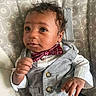 baby, child, infant, vest, bow_tie, clothing, curly_hair, patterned_background, hand, face, eyes, portrait, cute, indoors, sitting, expression, fashion, person, young, adorable