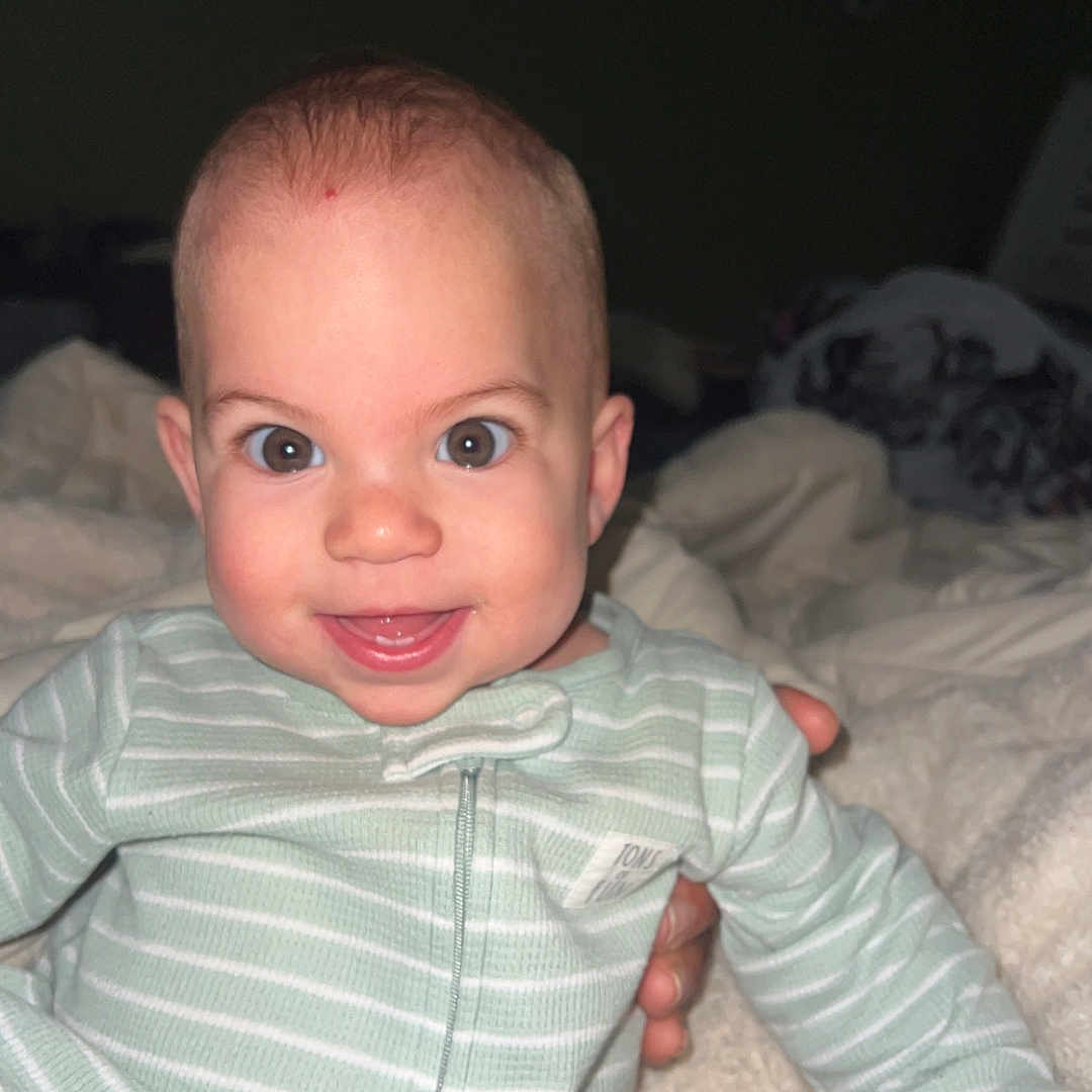 Sarahanne is registered to the contest to win money with this photo: baby, bed, bedroom, bodypart, clothing, face, finger, furniture, hand, happy, head, indoors, laughing, newborn, person, photography, portrait, room, shirt, smile