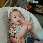 Easton is registered to the contest to win money with this photo: baby, infant, child, baby_seat, playful, foot, hand, face, curious, indoors, teddy_bear, toy, home, seat_belt, clothing, striped_shirt, shorts, person, cute, smile