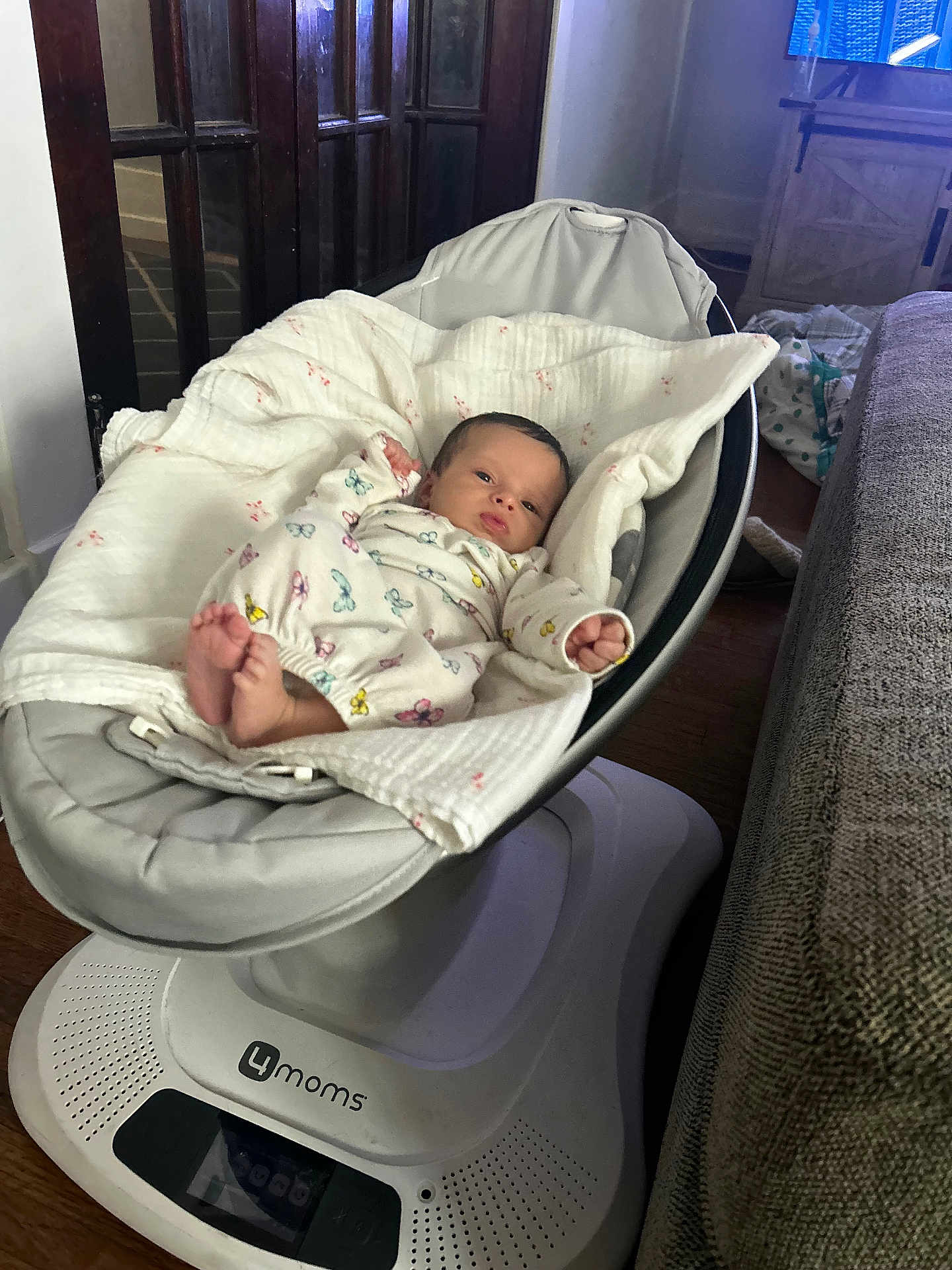 Elena is registered to the contest to win money with this photo: baby, infant, blanket, butterfly_print, baby_rocker, swaddled, face, indoor, wooden_floor, furniture, cushion, clothing, person, newborn, resting, cute, home, soft, peaceful, gazing