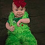 baby, child, clothing, costume, couch, cute, face, furniture, fuzzy, green_fur, happy, headband, indoor, infant, person, portrait, red_bow, sitting, smile, young