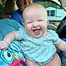 baby, child, infant, smiling, laughing, portrait, car, vehicle, indoors, adult, caregiver, family, onesie, clothing, unicorn_pattern, hands, seated, happy, close_up, daylight
