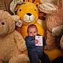 baby, infant, milestone_card, three_months, plush_toy, stuffed_animal, lion_toy, teddy_bear, bunny, onesie, cozy, nursery, soft_toys, cuddly, portrait, sitting, cheeks, hand, indoor, warm_lighting